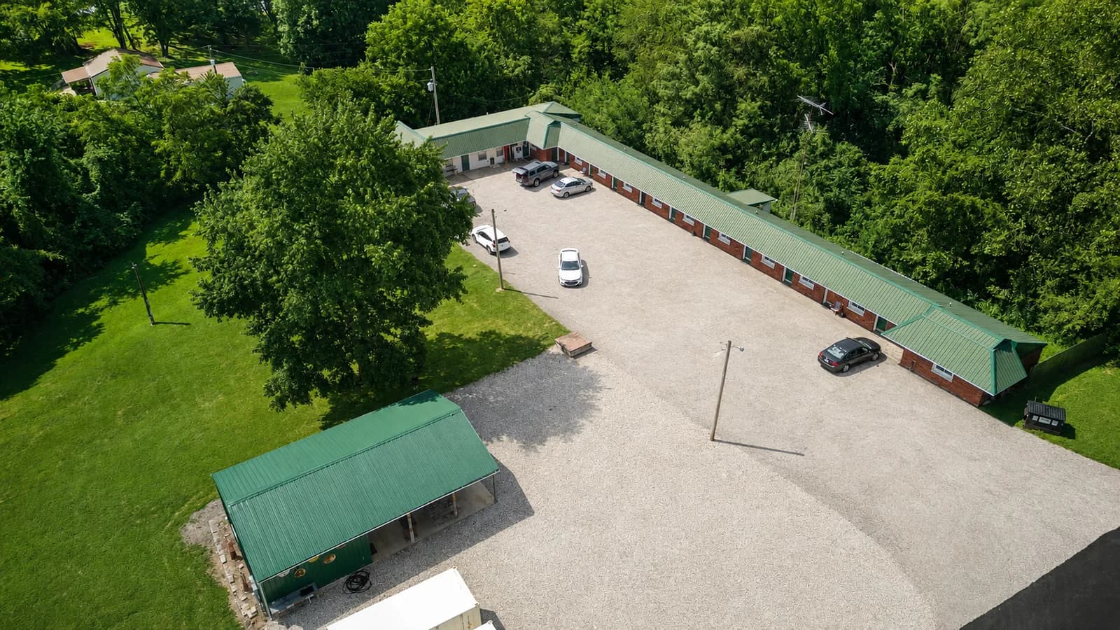 Aerial view of Spring Haven Motel's L-shaped building, parking lot, and covered pavilion