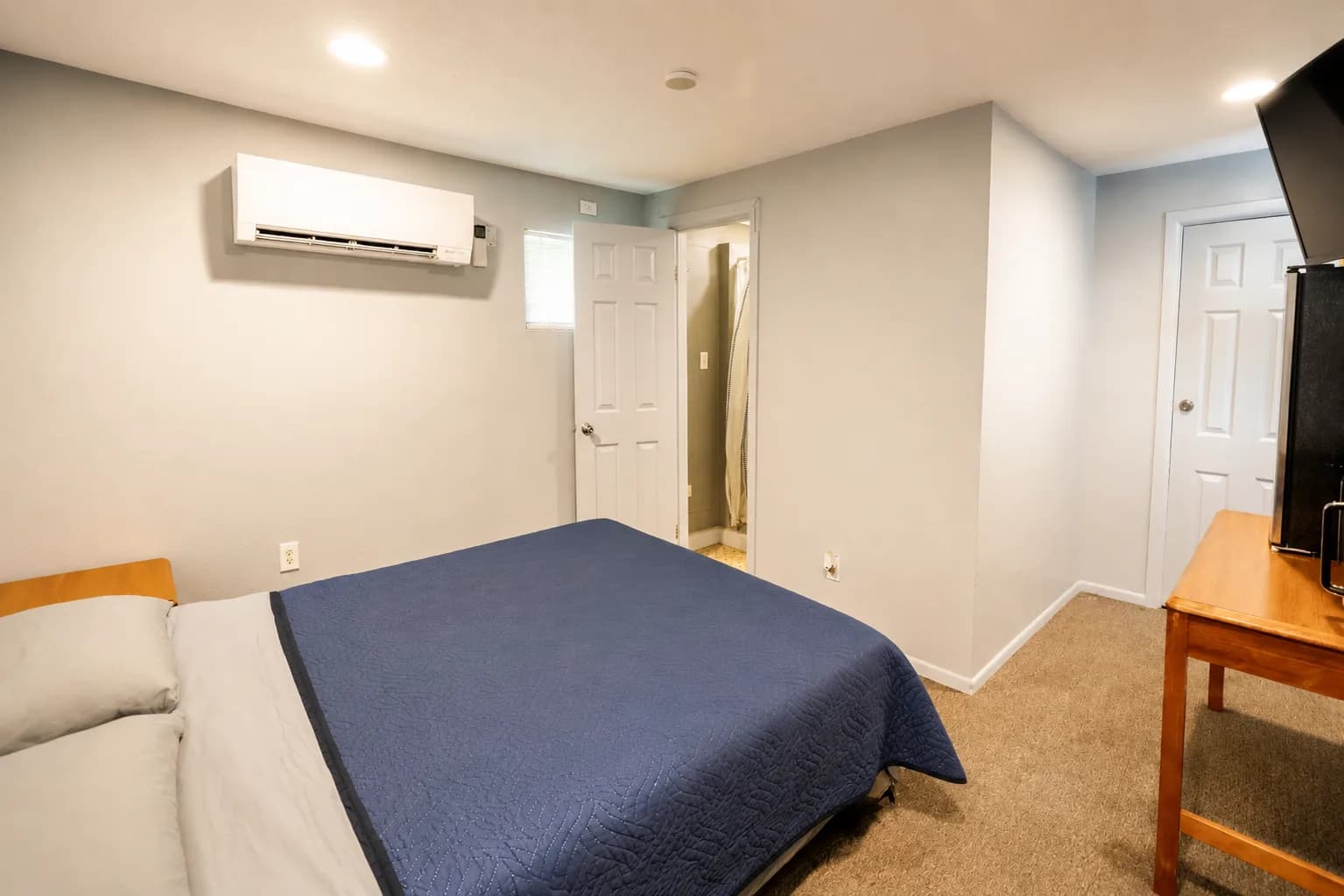 Guest room with a queen bed, ductless air conditioning, and an open bathroom door