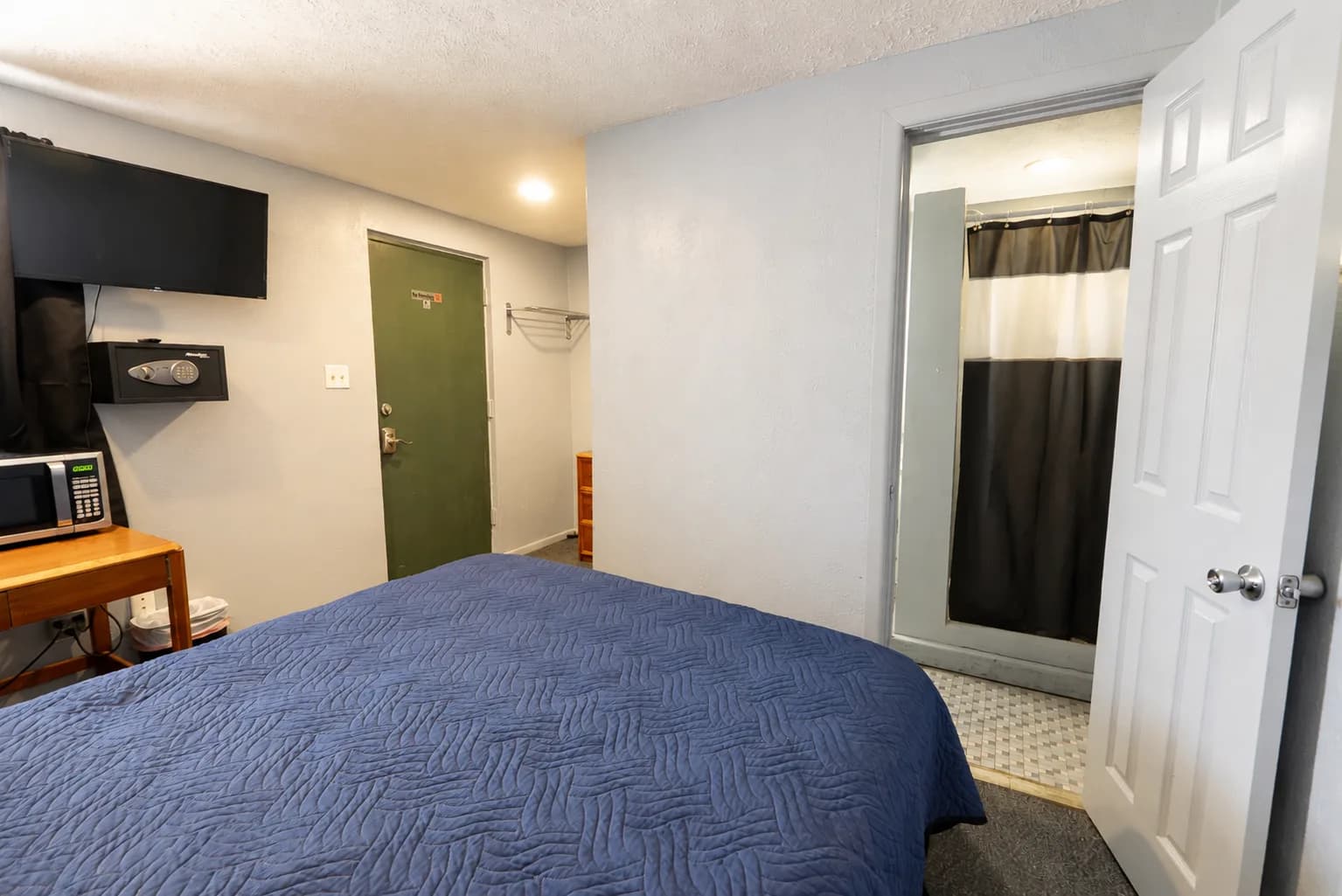 Guest room with a queen bed and the private bathroom door open