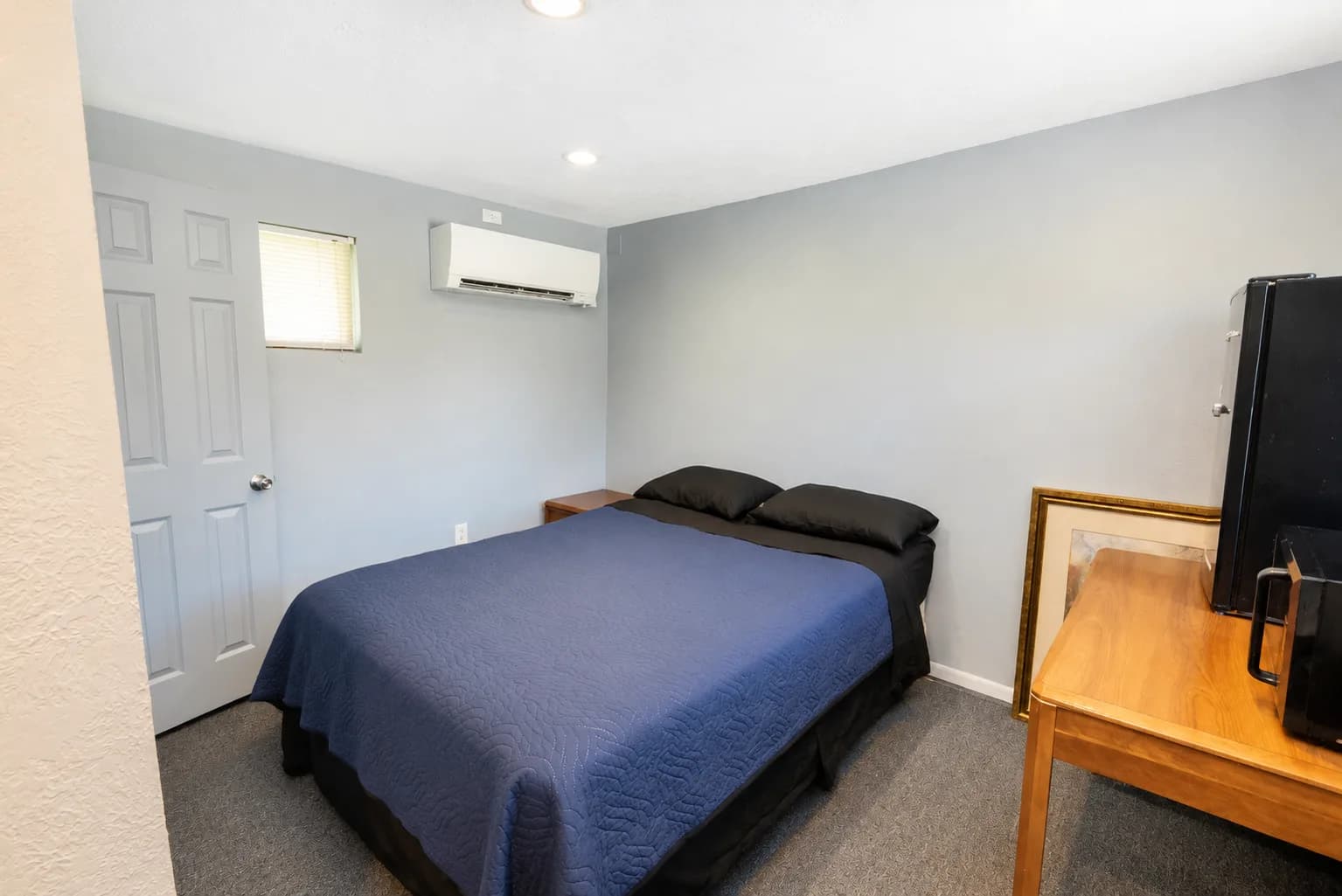 Guest room with a queen bed and a wall-mounted flat screen TV