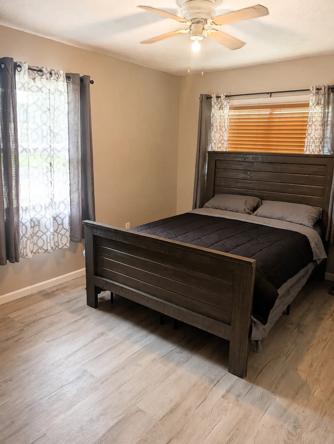 Suite bedroom with a queen bed between two curtained windows