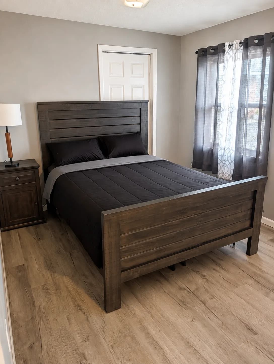 Suite bedroom with a dark wood bed frame and hardwood-style flooring