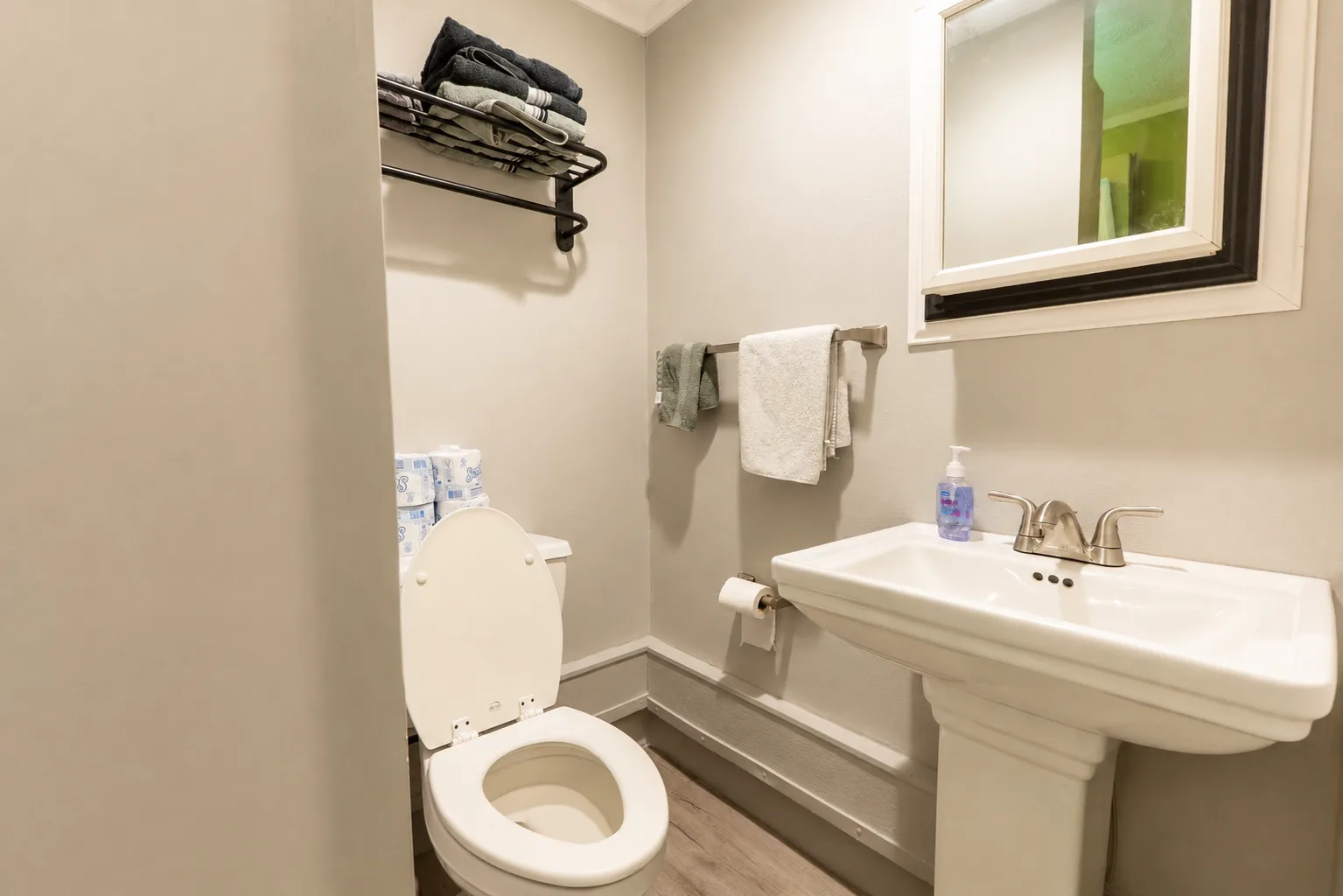 Suite bathroom with a pedestal sink, mirror, and stocked towel rack