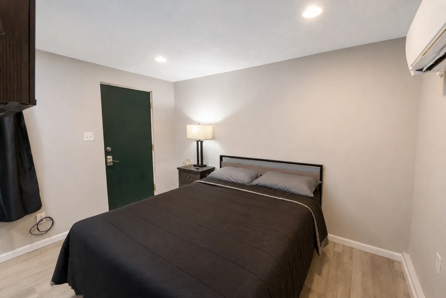 Suite bedroom with a queen bed, bedside lamp, and nightstand
