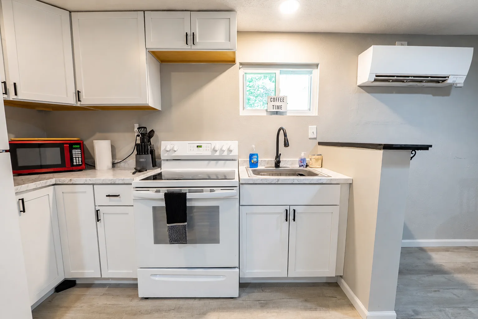 Full suite kitchen with a range, microwave, sink, and white cabinetry