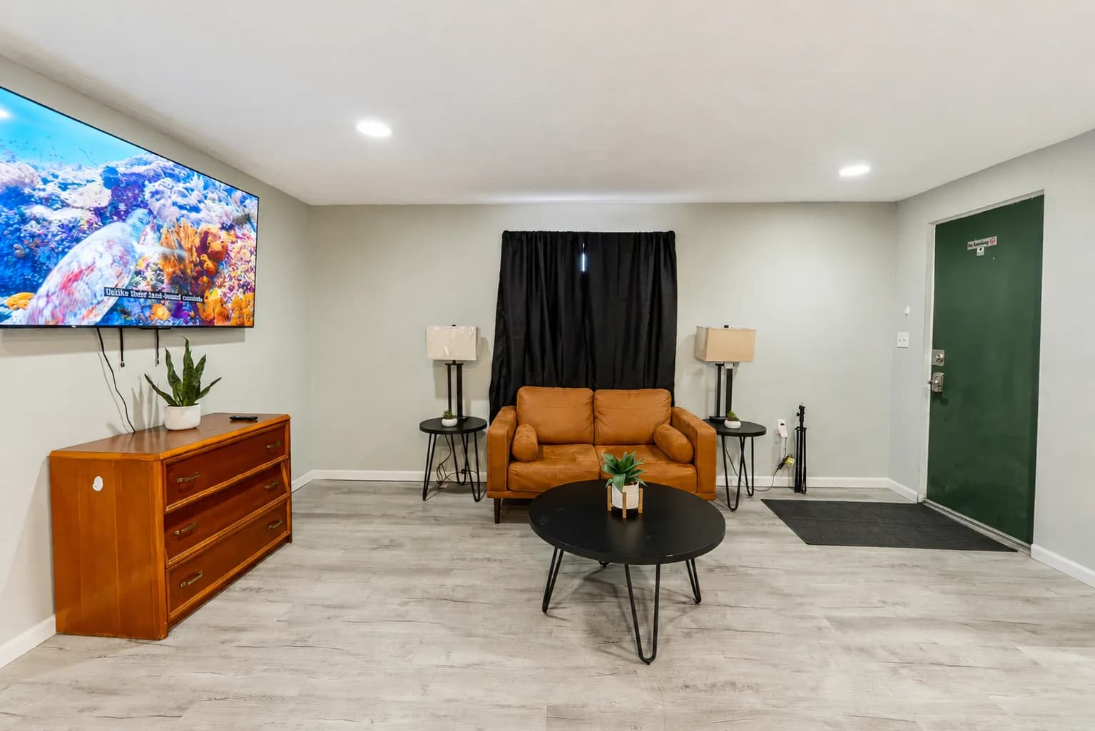 Suite living room with a leather sofa, coffee table, and large wall-mounted TV